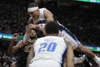 Orlando Magic forward Paolo Banchero, center, falls between Cleveland Cavaliers forward Evan Mobley, left, and teammate Markelle Fultz (20) after committing an offensive foul on Isaac Okoro in the second half of Game 7 of an NBA basketball first-round playoff series, Sunday, May 5, 2024, in Cleveland. (AP Photo/Sue Ogrocki)