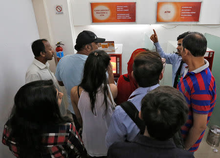 A security guard speaks to customers after a cash deposit machine stopped working at a bank in Mumbai, India, November 8, 2016. REUTERS/Danish Siddiqui