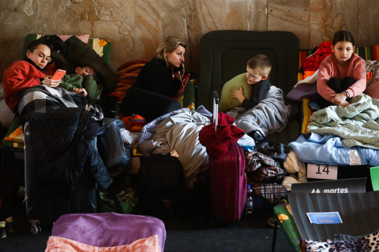 People huddle under blankets at a railway station.