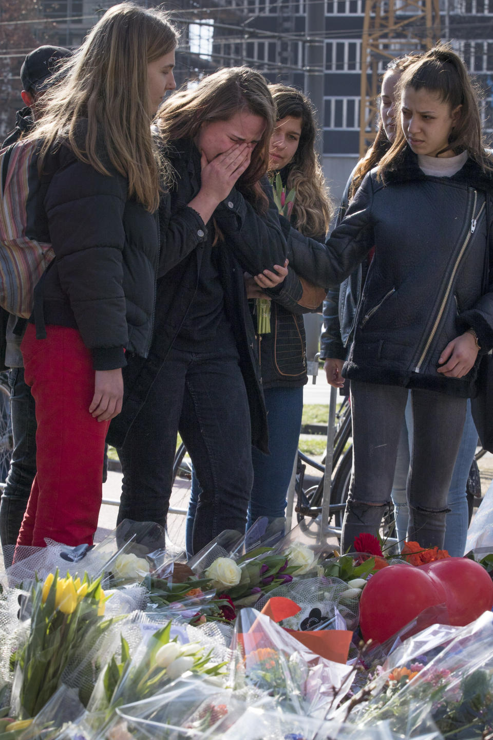 A mourner weeps after putting flowers at the site of a shooting incident in a tram in Utrecht, Netherlands, Tuesday, March 19, 2019. A gunman killed three people and wounded others on a tram in the central Dutch city of Utrecht Monday March 18, 2019. (AP Photo/Peter Dejong)