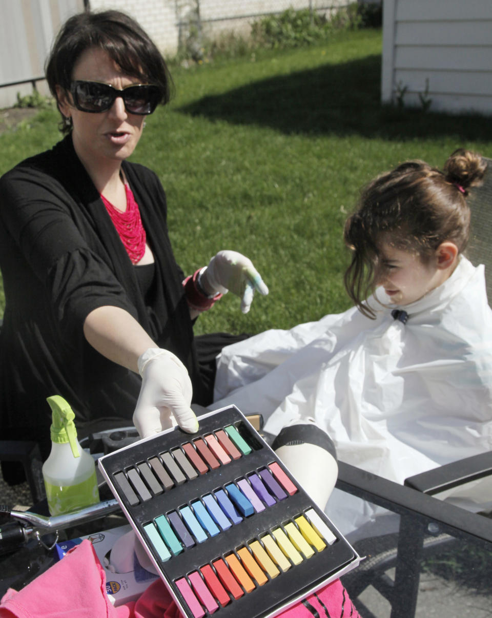 In this photo taken, Monday, April 2, 2012, neighborhood mom Orly Telisman, of Chicago, prepares to color eight-year-old Gabriella Lujan's hair with soft pastel chalk. Everyone from hipsters to children to Hollywood celebrities is embracing the runway fad for brightly colored hair, using soft pastel chalk.(AP Photo/M. Spencer Green)