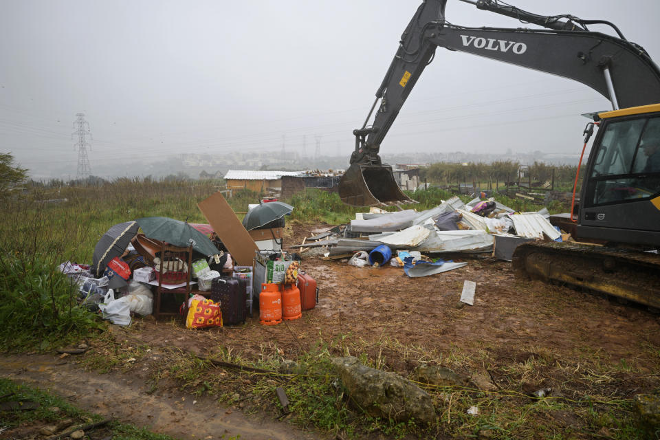 FILE - the belongings of a woman and her pregnant daughter are piled under the rain while an excavator destroys their makeshift house in Loures, outside Lisbon, Monday, March 6, 2023. Seven families, mostly immigrants from Sao Tome & Principe, were evicted and had their illegal houses demolished by municipal workers. They had built their houses in the last couple of years when unable to pay the rising rents being asked. (AP Photo/Armando Franca, File)