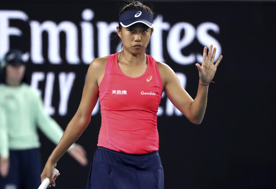 In this Jan. 20, 2020, photo, China's Zhang Shuai reacts after the ball hits the net during her first round singles match against United States' Sloane Stephens at the Australian Open tennis championship in Melbourne, Australia. It might just be the most insincere gesture in sports: A tennis player signals an apology after a ball clips the net tape and trickles over, producing a winner, an obviously accidental winner, to end a point. (AP Photo/Dita Alangkara)