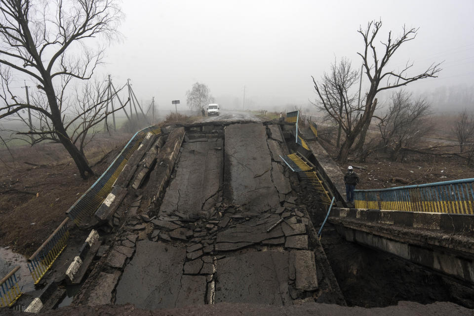 A motorcyclist looks at a bridge destroyed by the Russian army when it retreated from villages on the outskirts of Kyiv, Ukraine, Friday, April 1, 2022. (AP Photo/Rodrigo Abd)