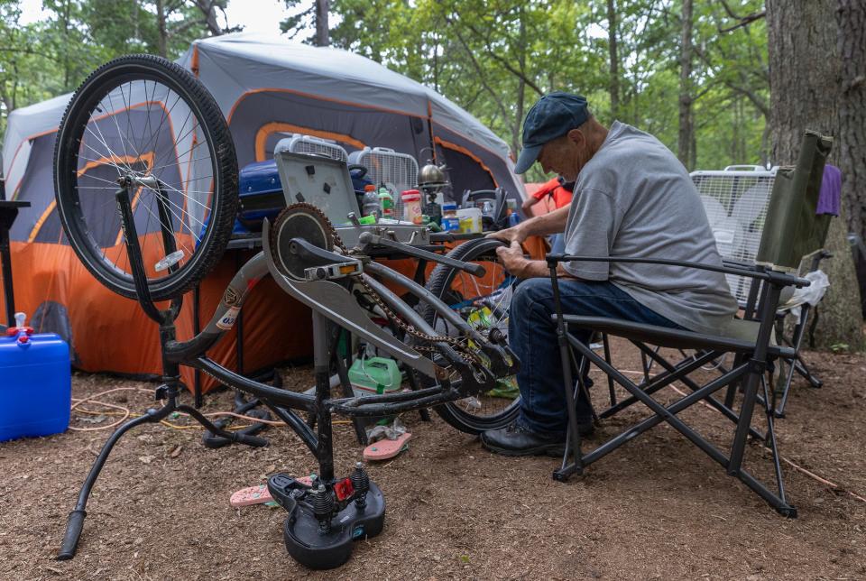 Robert Jamison works on changing a flat tire of one of the many bikes the campers use to get around the area. The camp itself has thorny vines that cause most of the flats. A homeless camp in the woods in Toms River on August 10, 2023