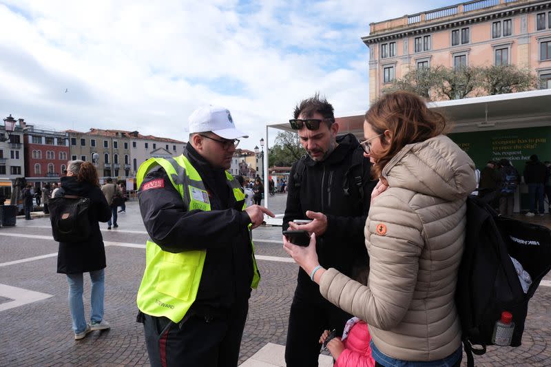 Tourists shows the QR code on a smartphone to prove their payment of a fee for day trippers introduced by Venice