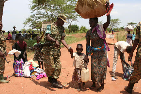 A Uganda People's Defence Forces (UPDF) soldier receives South Sudanese refugees crossing into Uganda at the Ngomoromo border post in Lamwo district, northern Uganda, April 4, 2017. REUTERS/Stringer