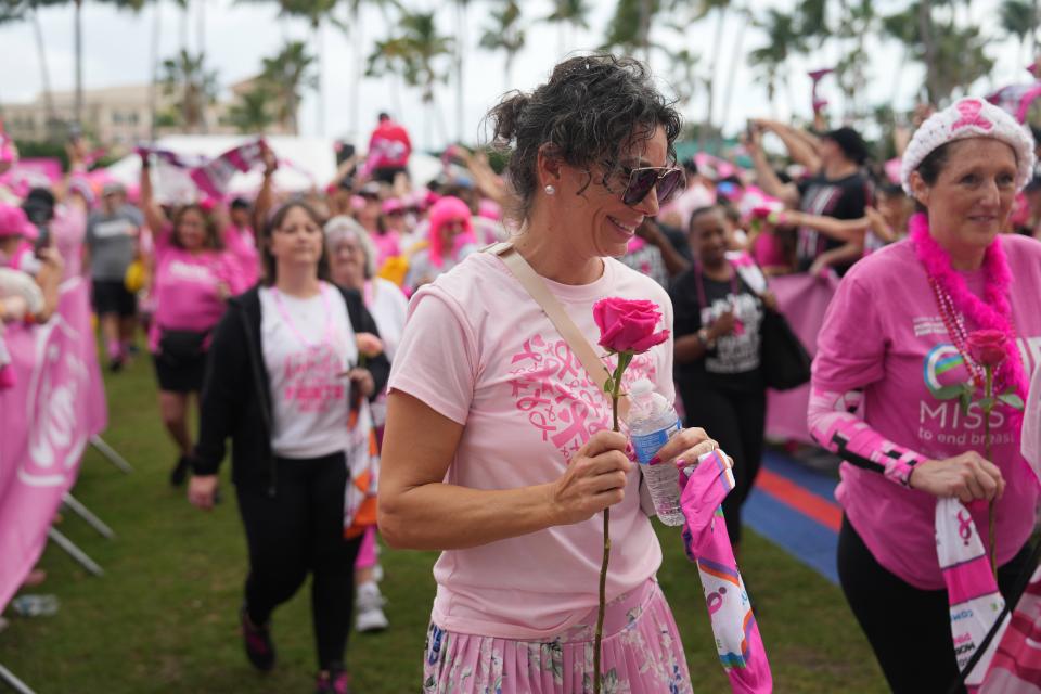 A participant in the Susan G. Komen More Than Pink Walk carries a red rose Saturday as she walks along Flagler Drive.