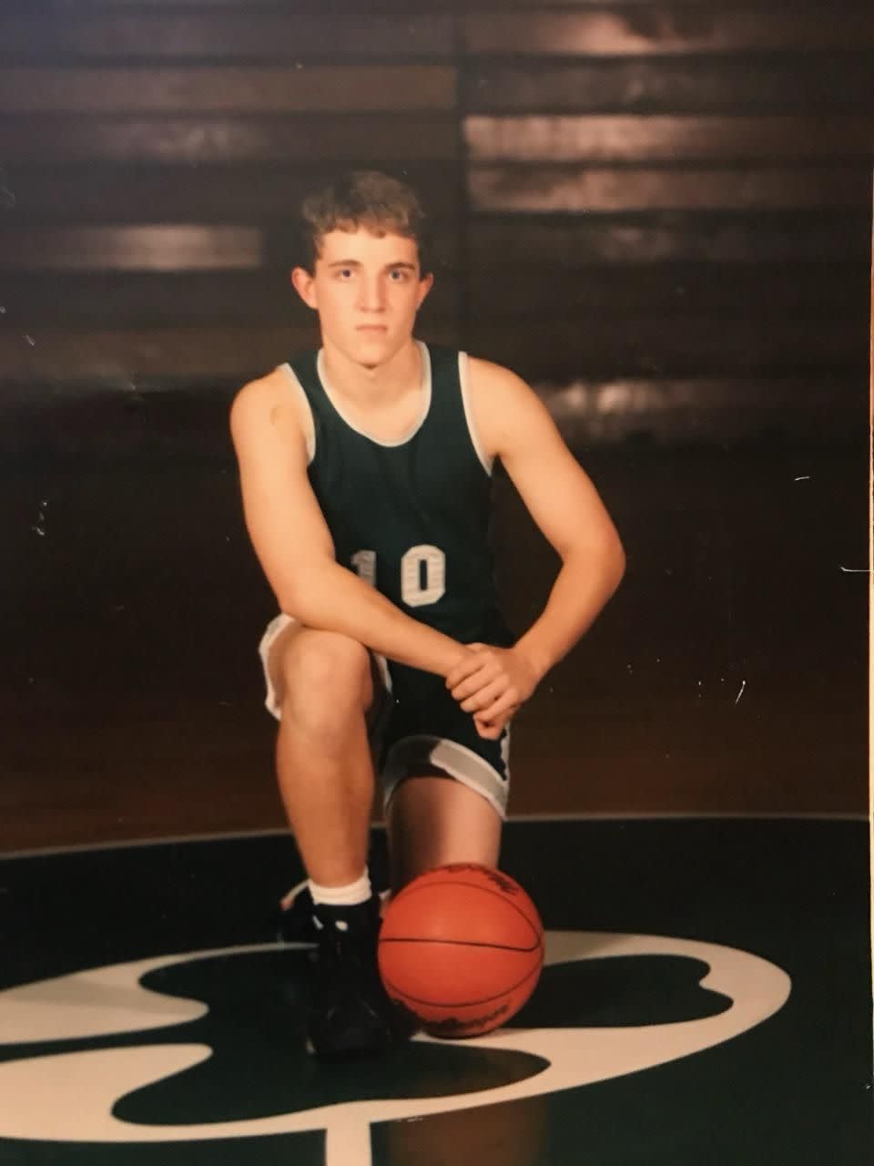 a boy kneeling down next to a basketball