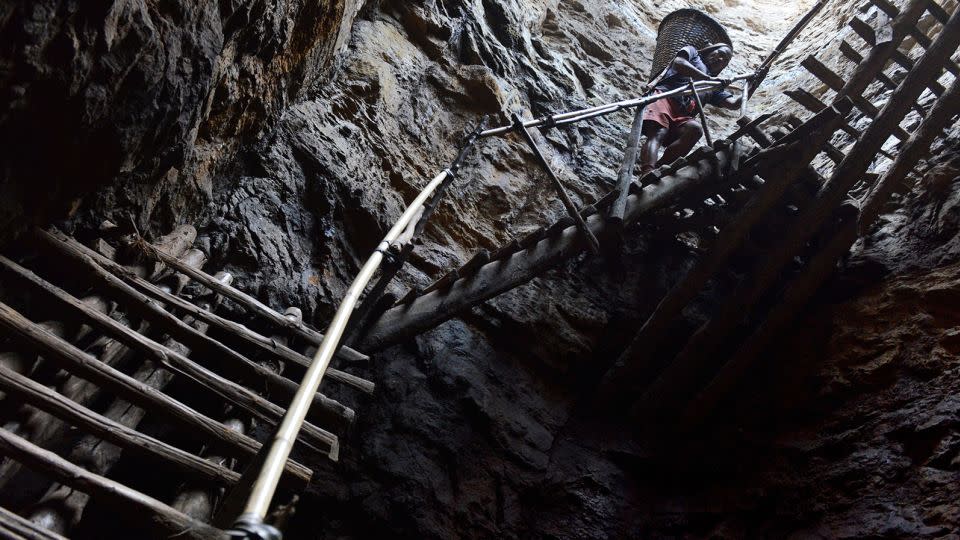 In this photograph taken on January 31, 2013, a miner slowly carries a heavy load of wet coal on a basket hundreds of feet up on wooden slats that brace the sides of a deep coal mine shaft near Rimbay village in the Indian northeastern state of Meghalaya. - Roberto Schmidt/AFP/Getty Images/File