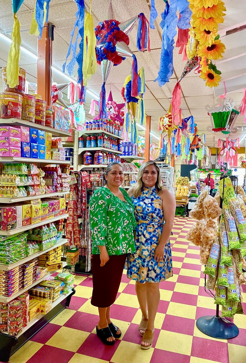 Beatriz Chaves (left) and her daughter, Estephanie Linares, stand inside Los Reyes, their colorful family grocery store and restaurant, on June 15, 2023.