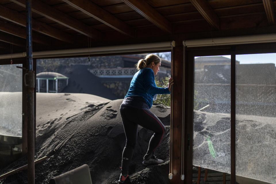 Cristina Vera leaves her house covered with ash from volcano eruptions after collecting her last belonging at the Canary island of La Palma, Spain, Monday, Nov. 1, 2021. A volcano on the Spanish island of La Palma that has been erupting for six weeks has spewed more ash from its main mouth a day after producing its strongest earthquake to date. (AP Photo/Emilio Morenatti)