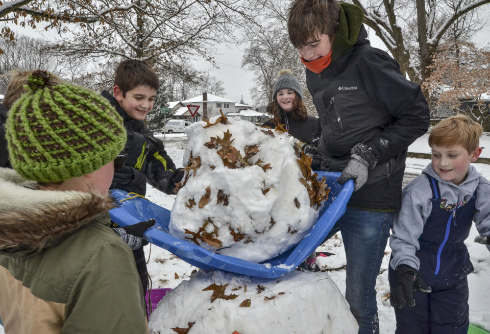 Andrew Kinne, center, helps a group of kids lift a snowball to create a snowman in Terre Haute, Ind., Monday, Dec. 16, 2019. (Austen Leake/The Tribune-Star via AP)
