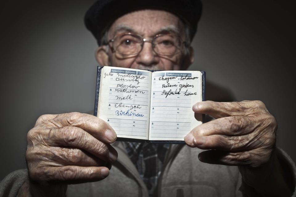 90 year old holocaust survivor Hy Abrams poses for a portrait with a book that he carries with him everyday that documents all the different concentration camps he was held in during the second World War, in the Brooklyn borough of New York January 15, 2015. In a little leather book, the kind some men use to list lovers, Holocaust survivor Hy Abrams keeps the names that still haunt him: Auschwitz, Plaszow, Mauthausen, Melk and Ebensee. It has been 70 years since the Soviet army liberated the Auschwitz concentration camp in Poland, where Abrams was taken at age 20 by German Nazi soldiers and separated from his mother, father, brother and three sisters. Picture taken January 15, 2015. To match AUSCHWITZ-ANNIVERSARY/USA REUTERS/Carlo Allegri (UNITED STATES - Tags: SOCIETY CONFLICT ANNIVERSARY TPX IMAGES OF THE DAY)