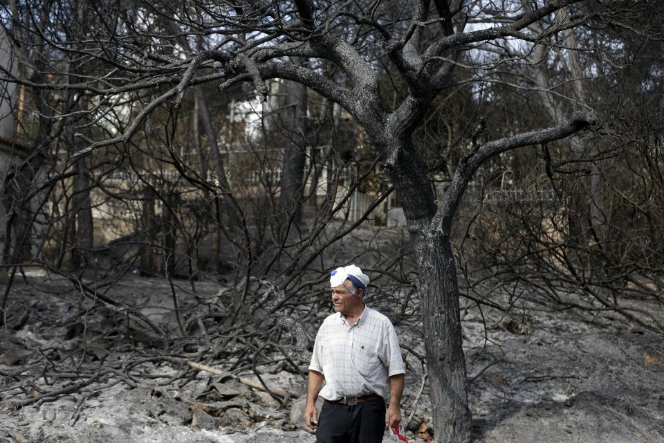 A local resident stands in front of a burned forest in Mati, east of Athens, Thursday, July 26, 2018. Rescuers intensified a grim house-to-house search Wednesday for more casualties from a deadly forest fire outside Athens, as the country's military said it was using footage from U.S. combat drones and surveillance aircraft to try to determine whether arsonists were behind the blaze and stop future attacks. (AP Photo/Thanassis Stavrakis)