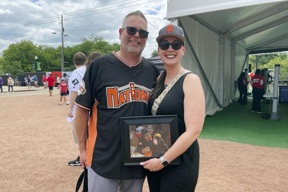 Ajay Stone , left, and his wife Christina pose with a photo of their daughter at 10-months old sitting next to Willie Mays, Thursday, June 20, 2024, at historic Rickwood Field in Birmingham, Ala.. They traveled from Charlotte, N.C. for the Negro League tribute baseball game. (AP Photo/Alanis Thames