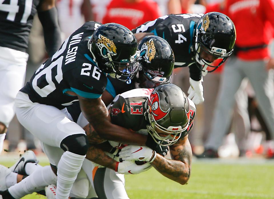 Dec 1, 2019; Jacksonville, FL, USA; Tampa Bay Buccaneers wide receiver Mike Evans (13) is tackled by Jacksonville Jaguars defensive back D.J. Hayden (25) and free safety Jarrod Wilson (26) and linebacker Donald Payne (54) during the first quarter at TIAA Bank Field. Mandatory Credit: Reinhold Matay-USA TODAY Sports