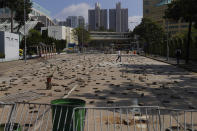 People walk by a road scattered with bricks and barricades set by pro-democracy protesters outside the Hong Kong Baptist University, in Hong Kong, Wednesday, Nov. 13, 2019. Police have increased security around Hong Kong and its university campuses as they brace for more violence after sharp clashes overnight with anti-government protesters. (AP Photo/Vincent Yu)