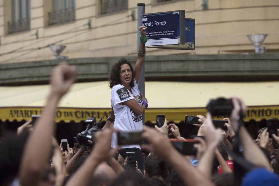 The widow of slain councilwoman Marielle Franco rises her fist during a demonstration marking the 7th month since her wife's murder in Rio de Janeiro, Brazil, Sunday, Oct. 14, 2018. Franco supporters distributed a thousand street signs in memory of her after a video on social media showed one being destroyed by two politicians with the right wing Social Liberal Party. (AP Photo/Leo Correa)