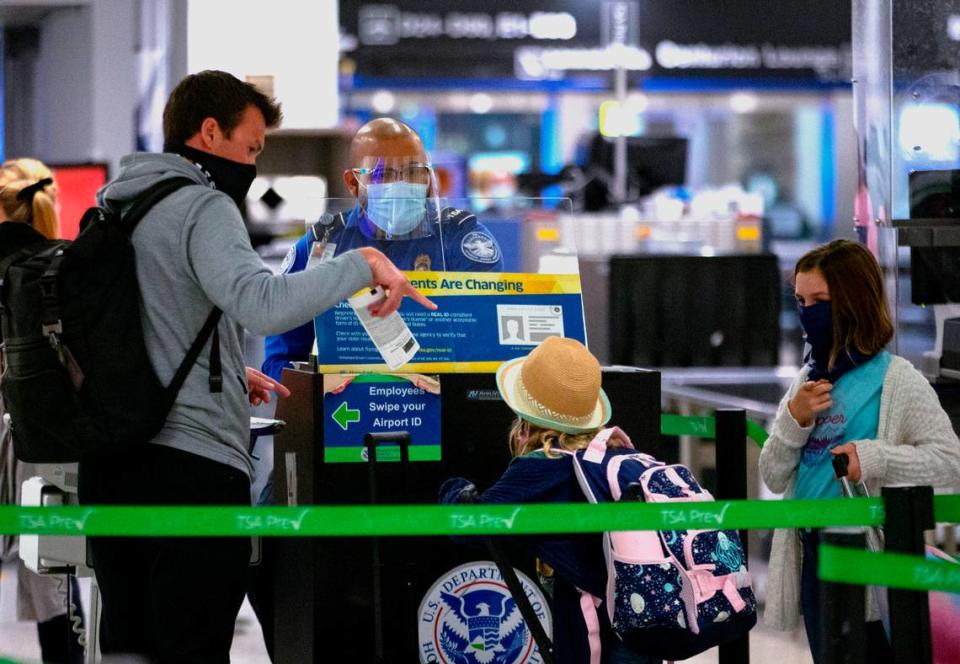 Un empleado de la TSA lleva una mascarilla mientras ayuda a los viajeros a pasar el puesto de seguridad en el Vestíbulo D del Aeropuerto Internacional de Miami, el lunes 28 de diciembre de 2020, en Miami, Florida.