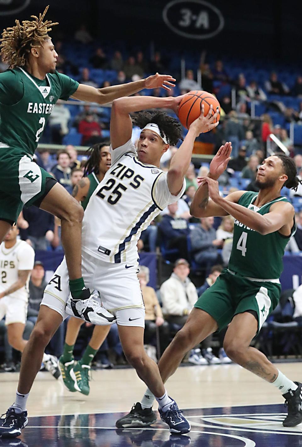 Akron's Enrique Freeman secures the ball against Eastern Michigan's Noah Farrakhan and Jalin Billingsley during the 2022-23 season.