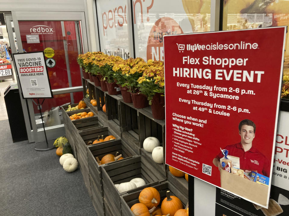 In this Thursday, Oct. 7, 2021, photograph, a sign advertising for workers stands outside a Hy-Vee grocery store in Sioux Falls, S.D. Companies that typically hire thousands of seasonal workers are heading into the holidays during one of the tightest job markets in decades, making it unlikely they’ll find all the workers they need. For shoppers, it might mean a less than jolly holiday shopping experience, with bare store shelves and online orders that take longer than usual to fill. (AP Photo/David Zalubowski)