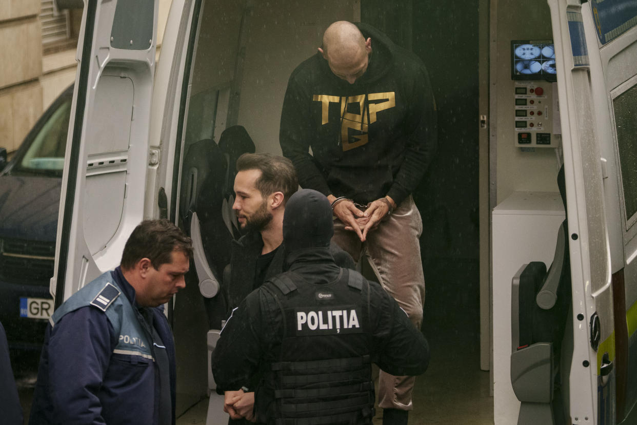 Police officers escort Andrew Tate, center, handcuffed, next to his brother Tristan to the Court of Appeal in Bucharest, Romania, Tuesday, March 12, 2024. Online influencer Andrew Tate was detained in Romania and handed an arrest warrant issued by British authorities, his spokesperson said Tuesday. (AP Photo/Andreea Alexandru)