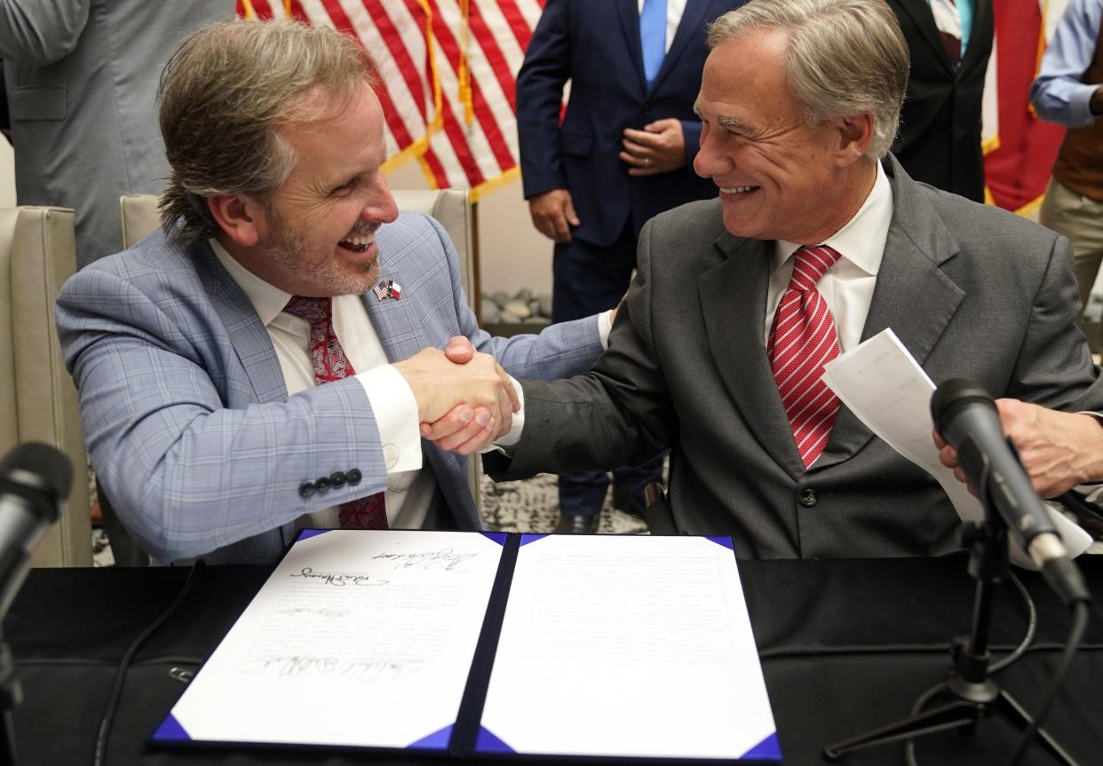 Texas Gov Greg Abbott and State Sen. Bryan Hughes, R-Mineola, shake hands after Abbott signed Senate Bill 1, also known as the election integrity bill, into law in Tyler, Texas, Tuesday, Sept. 7, 2021.  The sweeping bill signed Tuesday by the two-term Republican governor further tightens Texas' strict voting laws.