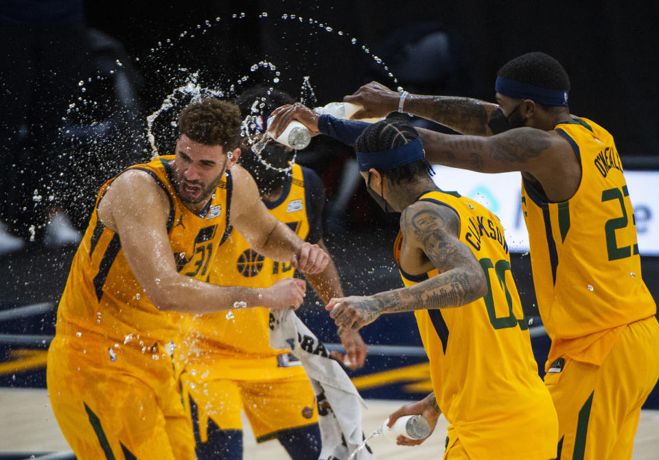 Utah Jazz's Mike Conley, rear, Royce O'Neale, right, and Jordan Clarkson (00) spray water on Utah Jazz forward Georges Niang (31) during his post-game interview following their NBA Basketball against the Charlotte Hornets Monday, Feb. 22, 2021, in Salt Lake City. (Rick Egan/The Salt Lake Tribune, via AP)