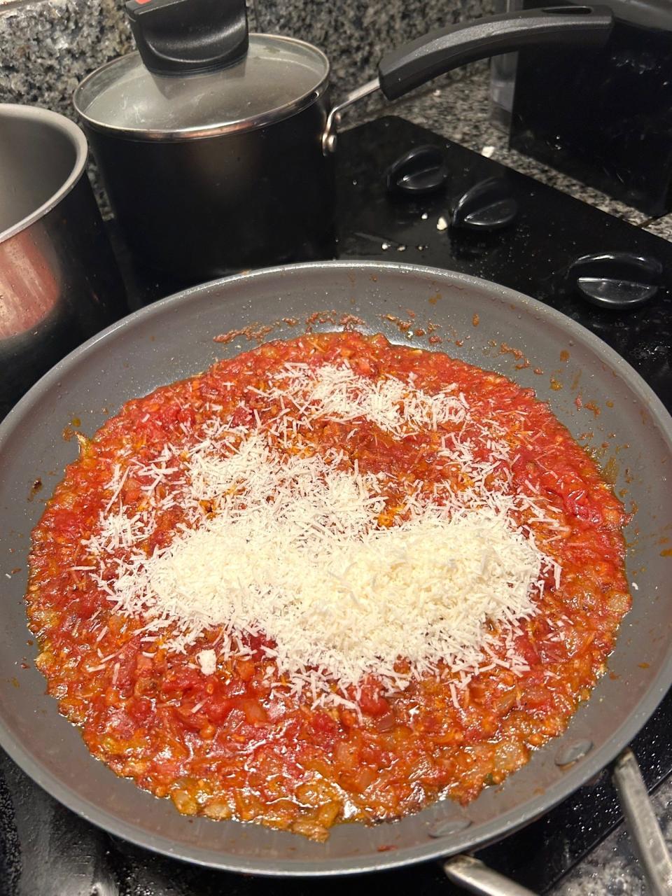 Adding cheese to the sauce for Giada De Laurentiis' Bucatini All'Amatriciana pasta