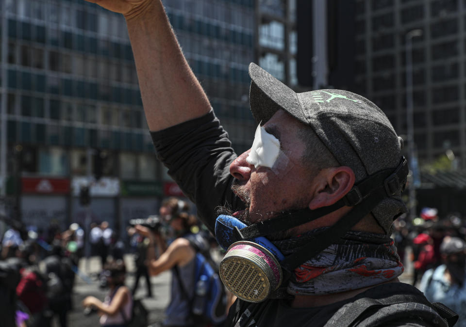 An anti-government demonstrator, who said a tear gas canister injured his eye, shouts slogans against the police near La Moneda presidential palace in Santiago, Chile, Tuesday, Nov. 12, 2019. Chile is entering its 26th day of protest against social inequality with huge demonstrations across the country and a national strike. (AP Photo/Esteban Felix)