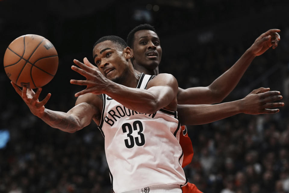 Brooklyn Nets' Nic Claxton (33) reaches for the ball next to Toronto Raptors' Christian Koloko during the second half of an NBA basketball game Wednesday, Nov. 23, 2022, in Toronto. (Chris Young/The Canadian Press via AP)