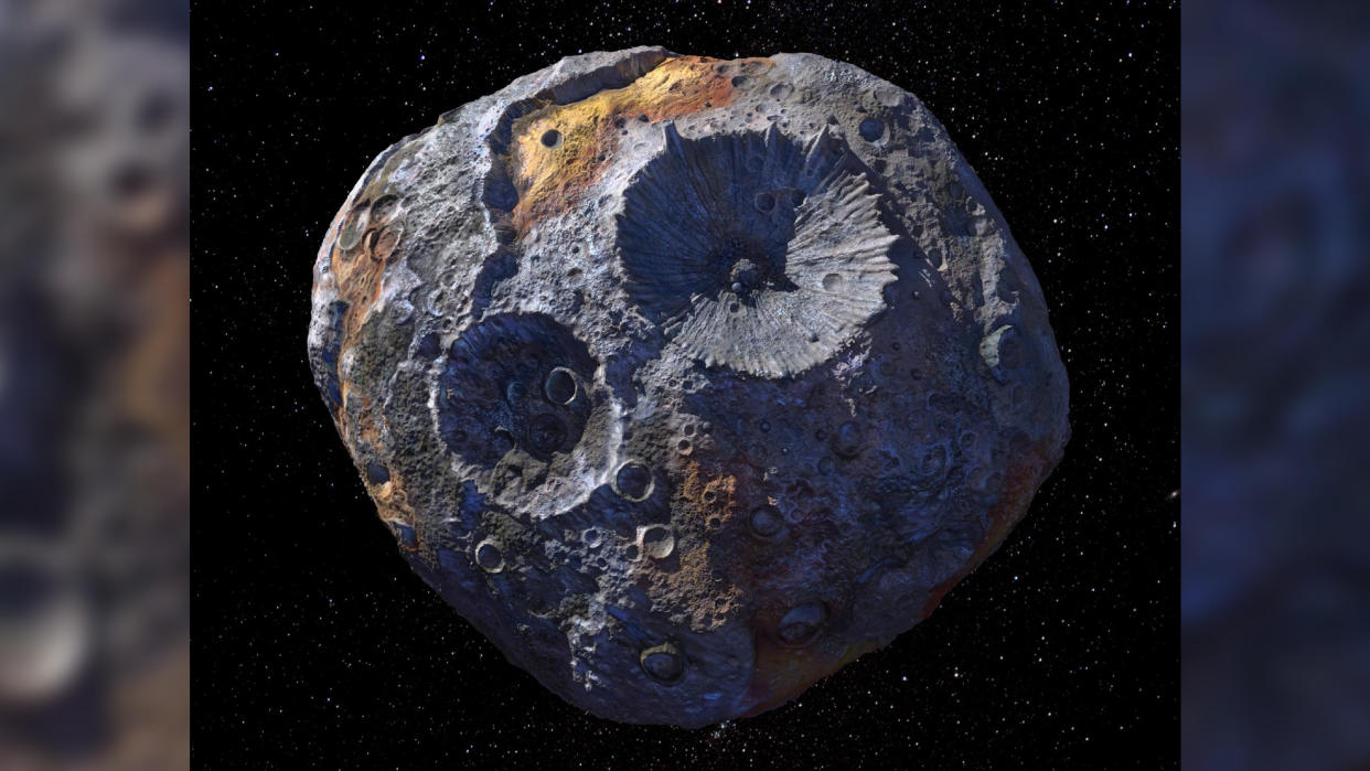  A large gray space rock with large craters on the surface and patches of brown material. . 