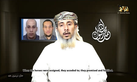 Nasser bin Ali al-Ansi, a leader of the Yemeni branch of al Qaeda (AQAP), speaks as an image of brothers Cherif Kouachi (rear L) and Said Kouachi (rear R), who carried out the Charlie Hebdo attack, is seen in this still image taken from a social media website on January 14, 2015, which purports to show Al Qaeda in Yemen claiming responsibility for the attack on the French satirical newspaper. REUTERS/YouTube via Reuters TV
