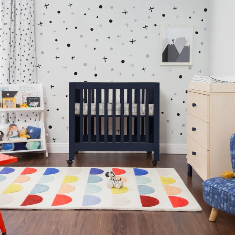 Dark navy crib with even sides and wheels with colorful halve circle rug