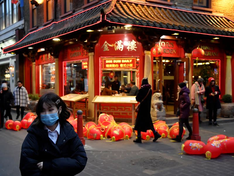 A woman wears a mask in Chinatown district, in London