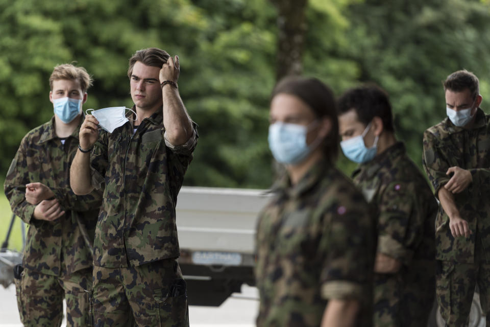 21 year old Swiss Ice Hockey player Nico Hischier, second from left, , center at NHL club New Jersey Devils, puts on his protection mask next to his fellow recruits after receiving his Swiss army uniform in Wangen an der Aare, Switzerland, Tuesday, June 16, 2020. Hischier completes part of his mandatory army service for elite athletes with an 18 week recruit training. (Alessandro della Valle/Keystone via AP)