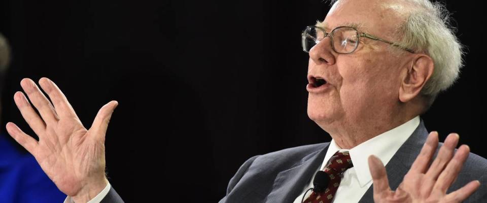 Warren Buffett speaks with hands up, gesturing