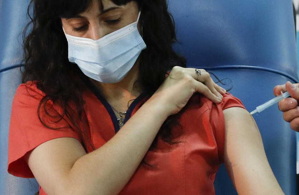 Dr. Estefania Zevrnja gets a shot of Russia's Sputnik V vaccine for COVID-19 at Dr. Pedro Fiorito Hospital in Avellaneda, Argentina, Tuesday, Dec. 29, 2020. (AP Photo/Natacha Pisarenko)