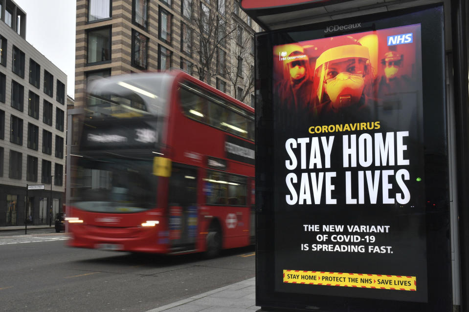 A London Transport famous red bus London passing a Covid-19 sign during England's third national lockdown to curb the spread of coronavirus, in London, Friday, Jan. 8, 2021. (Dominic Lipinski/PA via AP)