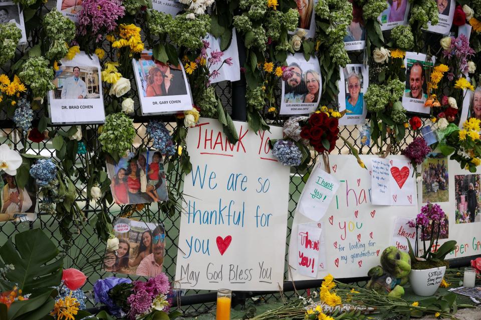 Signs, flowers and messages pinned to a fence as part of a vigil for victims of the Surfside, Miami condo collapse.