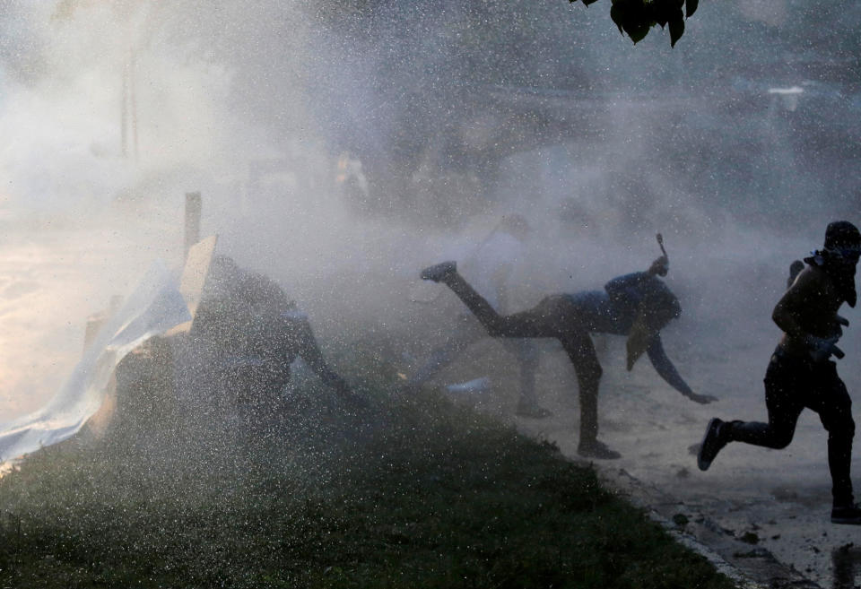 <p>Opposition party supporters are hit by a water cannon while clashing with riot security forces during a rally against President Nicolas Maduro in Caracas, Venezuela, May 18, 2017. (Marco Bello/Reuters) </p>