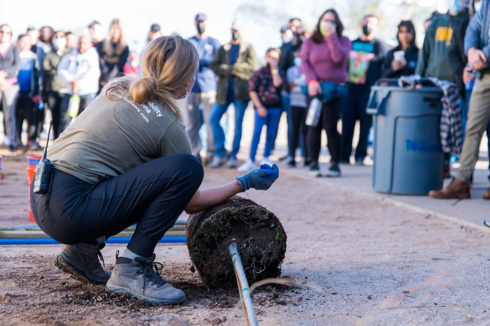 Arizona Sustainability Alliance programs manager Kayla Killoren demonstrates how to plant a tree for volunteers that will be planting 100 trees and other plants at an AZSA event at Emerson Elementary School in Phoenix, Ariz., on Feb. 27, 2022.