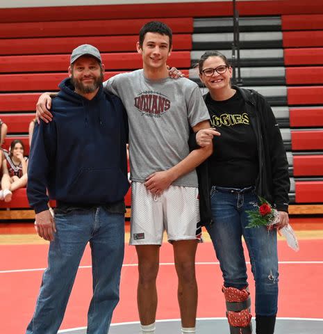 <p>Courtesy of Madison Rawlings </p> Noah Presgrove (center) with his parents, Victor Presgrove and Kasey Elliot, at his wrestling team's senior night.
