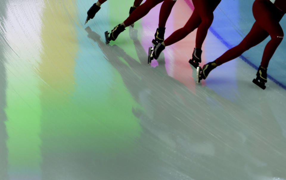 Polish speed skaters pass over a reflection on the ice from a screen above, during a training session at the 2014 Winter Olympics in Sochi, Russia, Feb. 20, 2014. 