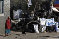 A woman walks her dog along a barricade in downtown Slovyansk , eastern Ukraine, Wednesday, April 16, 2014. The city of Slovyansk has come under the increasing control of the pro-Russian gunmen who seized it last weekend. The Slogans read: "No to Fascism, Yes to referendum, Soldier do not shoot." (AP Photo/Sergei Grits)