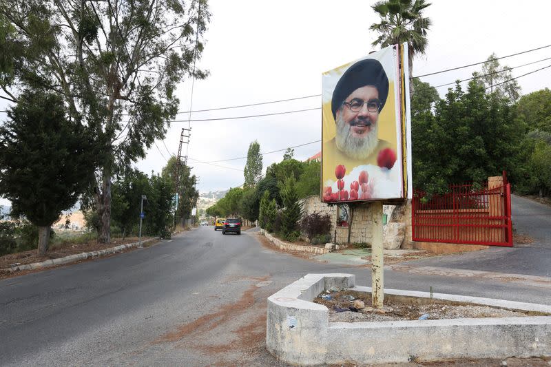 Cars drive near a poster depicting Lebanon's Hezbollah leader Sayyed Hassan Nasrallah at the entrance of the village of Ain Qana