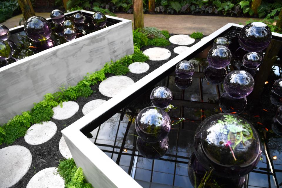 Glass balls appearing to float on water, together with a path of stepping stones carry on Yayoi Kusama's signature use of polka dots in the Tropical Conservatory.