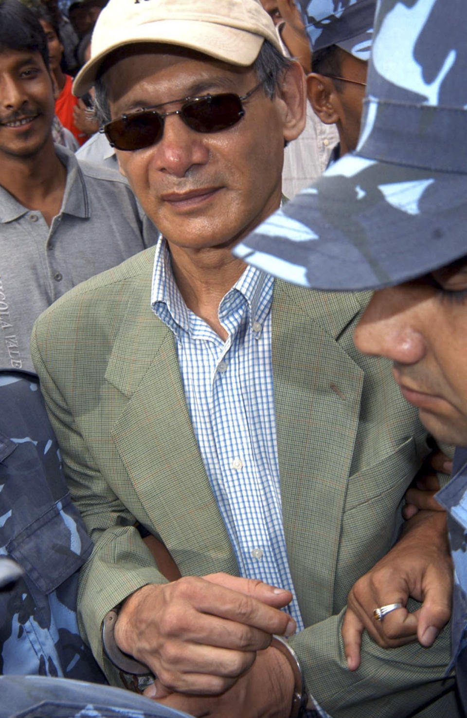 FILE - Police escort convicted French serial killer Charles Sobhraj from court in Katmandu, Nepal on Aug. 12, 2004. Confessed serial killer Sobhraj, who was convicted and sentenced to life in prison in Nepal, was ordered Wednesday, Dec. 21, 2022, to be released because of poor health, good behavior and having already served most of his sentence. (AP Photo/Binod Joshi, File)