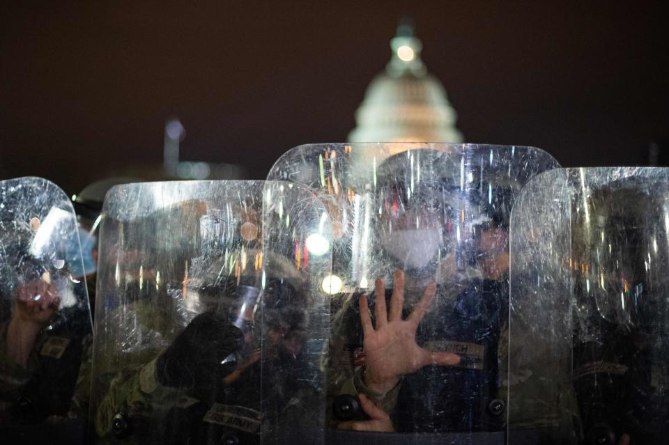 National Guard troops are seen behind shields as they clear a street from protestors outside the Capitol building on Wednesday in Washington, DC. Donald Trump's supporters stormed a session of Congress to certify Joe Biden's election win, triggering unprecedented chaos and violence at the heart of American democracy and accusations the president was attempting a coup.